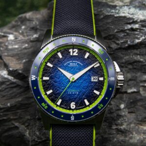 Eine robuste, elegante Armbanduhr mit blauem Zifferblatt und markanten grünen Akzenten auf Stein.