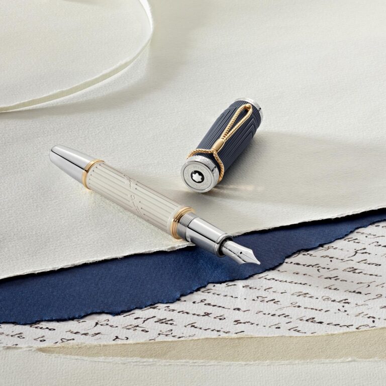 Füllfederhalter mit Silber- und Goldakzenten auf geschichtetem Papier in Blau und Beige.
