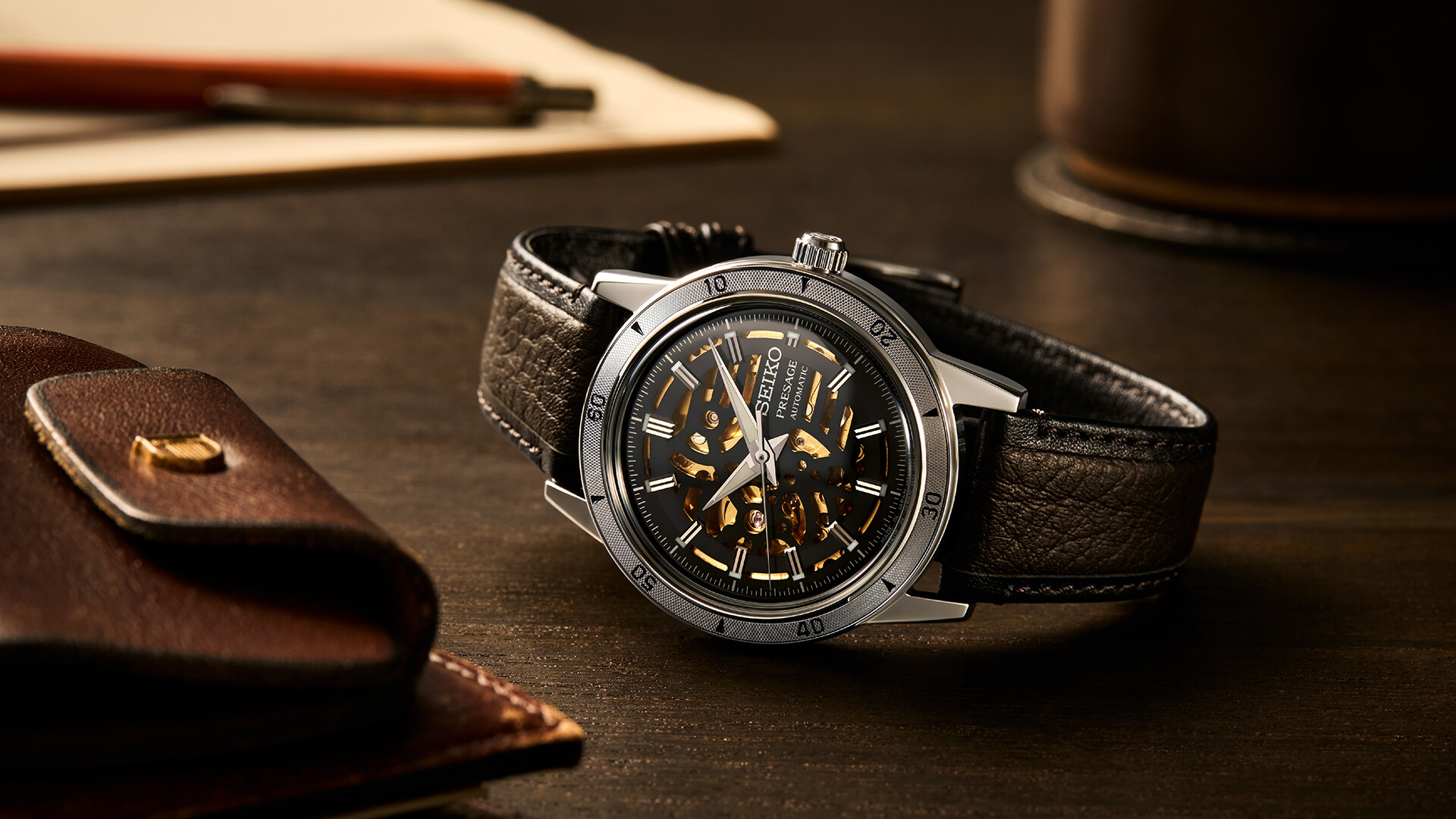 Eine elegante Armbanduhr mit dunklem Lederband, silbernem Gehäuse und offenem Uhrwerk.