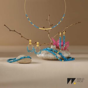 Blaue und goldene Schmuckstücke sind dekorativ auf Ästen arrangiert.