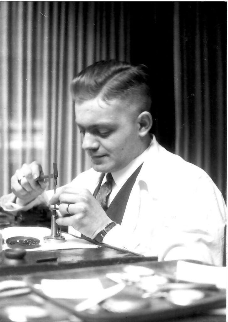 Ein junger Mann mit konzentriertem Blick arbeitet im weißen Kittel an einem Gerät