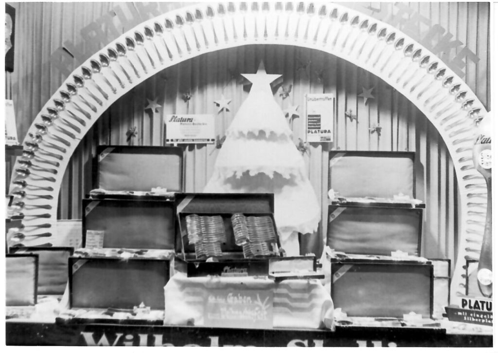 Eine festlich dekorierte Schaufensterauslage mit Besteck und Koffern in Schwarzweiß